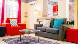 Una sala de estar con un sillón rojo, un sofá gris y una mesa de centro.
