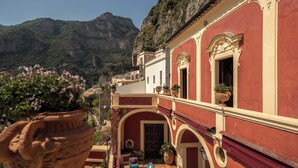 Un edificio con fachada roja, ventanas arqueadas y balcones con macetas.