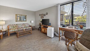 A living room with a sofa, TV, and a desk with a computer.