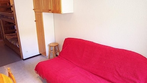 A room with a red sofa, a wooden stool, and a bunk bed. - 300m from ski slopes, 1st floor, balcony, 24m², Vars (Vars)
