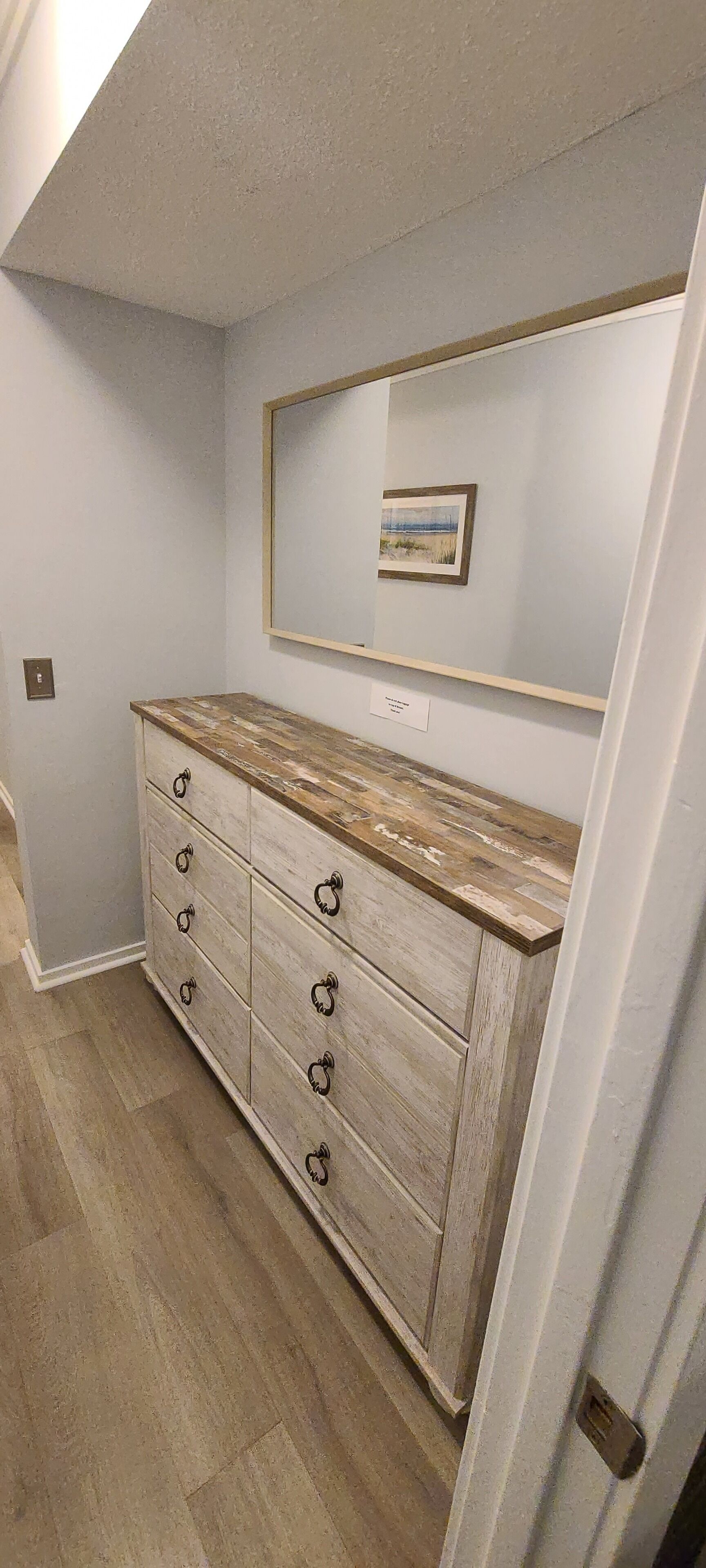 Une salle de bain avec un meuble-lavabo en bois, un miroir et un tableau encadré au mur.