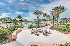 A resort with a circular seating area, palm trees, and a pool in the background.