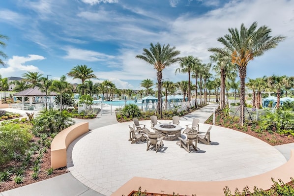 A resort with a circular seating area, palm trees, and a pool in the background.