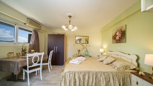 A bedroom with a bed, bedside table, lamp, and a desk with a chair. - KYVELI SUPERB SEA VIEW APARTMENT (ΑΡΓΟΣΤΟΛΙ)