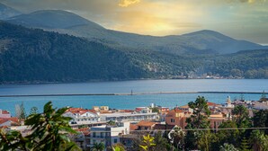 A coastal town with buildings, a body of water, and mountains in the background. - KYVELI SUPERB SEA VIEW APARTMENT (ΑΡΓΟΣΤΟΛΙ)