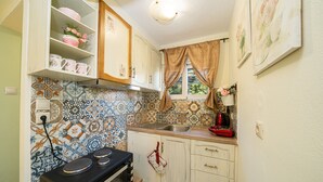 A kitchen with a stove, sink, and decorative tiles. - KYVELI SUPERB SEA VIEW APARTMENT (ΑΡΓΟΣΤΟΛΙ)