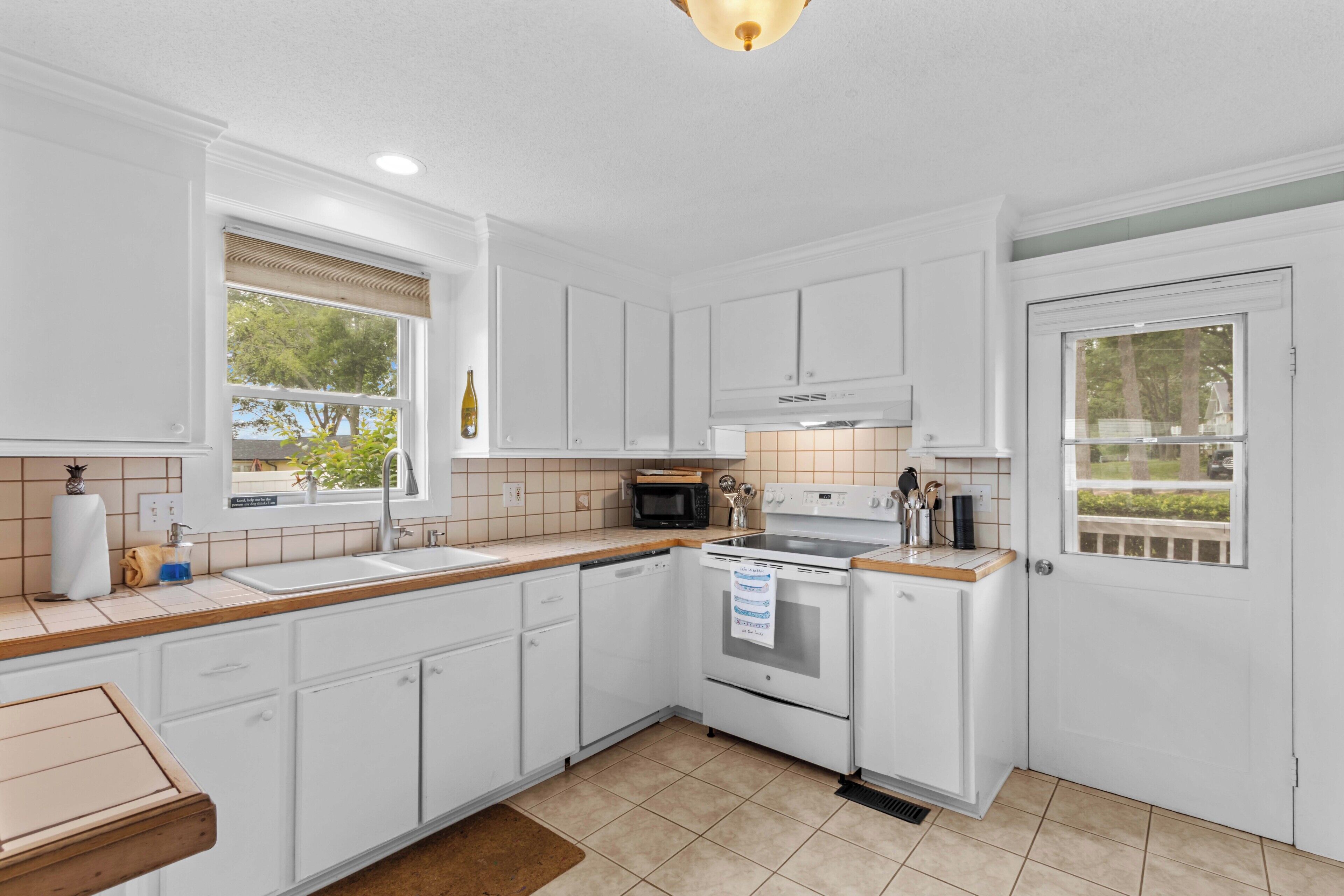 A kitchen with white cabinets, a microwave, an oven, and a sink.
