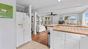 A modern kitchen with white cabinetry, a wooden countertop, and a view of the living room. - Cottage At Sunset Key (Terrell)