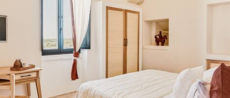 A bedroom with a bed, a desk, a wardrobe, and a window with curtains.