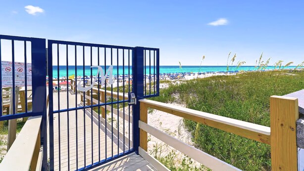 A wooden deck with a metal gate leading to a beach. - Pet-Friendly Gulf Front Condo • Free Beach Setup • 2 Pools + Hot Tub (Miramar Beach)