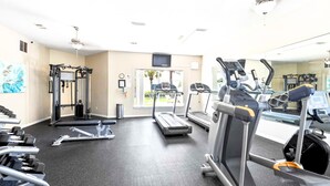 A gym with treadmills, weight machines, and a mirror. - Pet-Friendly Gulf Front Condo • Free Beach Setup • 2 Pools + Hot Tub (Miramar Beach)