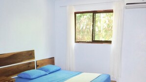 Ein Schlafzimmer mit zwei Betten, einem Deckenventilator, einem Fenster mit Vorhängen und einem Fliesenboden.