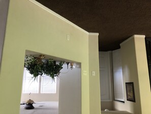 A room with a light green wall, a ceiling with a brown texture, and a window with blinds. - Beaches at the Airport (Jacksonville)