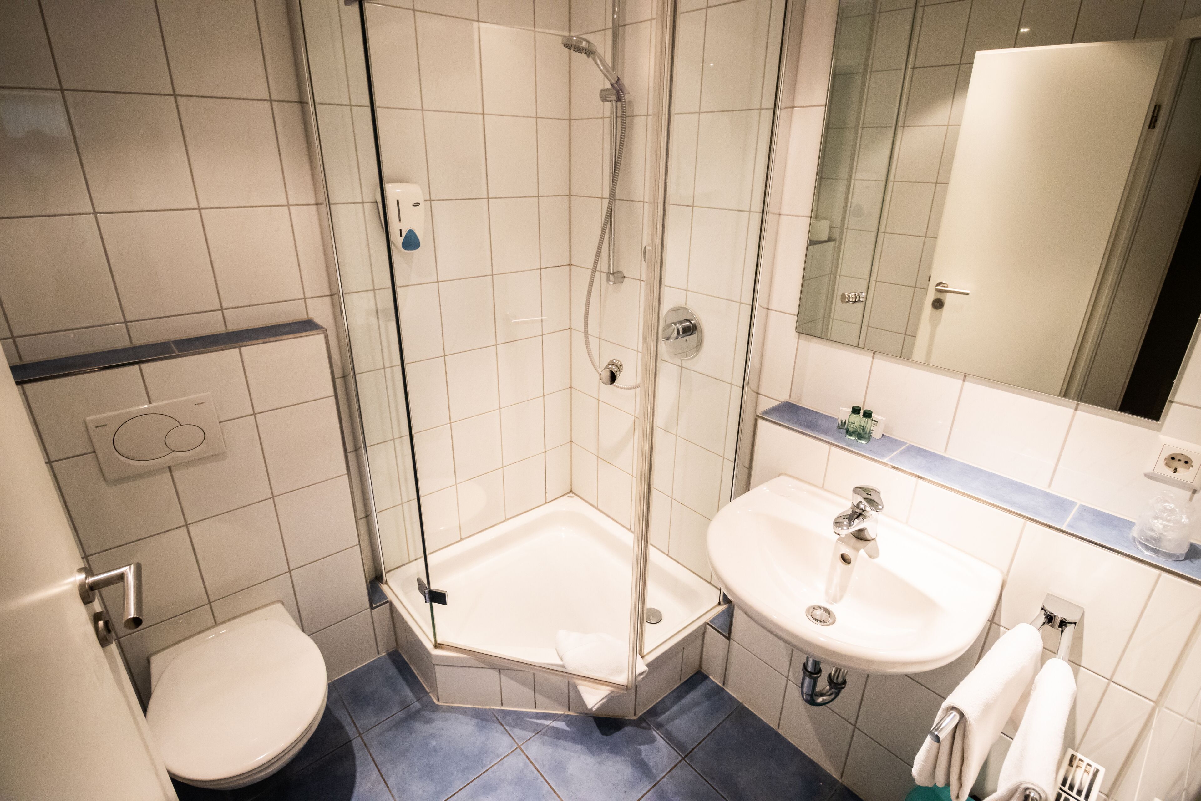 Une salle de bain moderne avec une douche à parois de verre, un lavabo blanc et des toilettes.