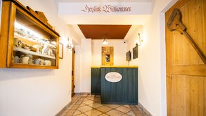 A hallway with a reception desk labeled "Rezeption" and a wooden door with a sign. - Hotel Gasthof Rössle (Weingarten)