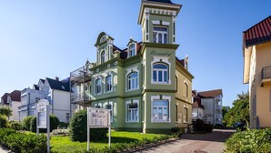 Un edificio histórico con una torre destacada, un letrero y un jardín bien cuidado.