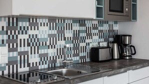 Una cocina moderna con protector contra salpicaduras de azulejos, pileta de acero inoxidable y cafetera.