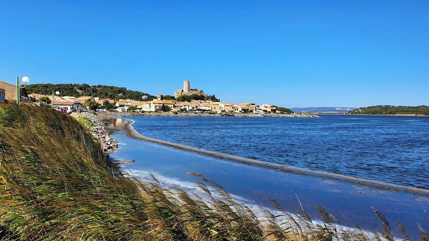 Un pueblo costero con una torre destacada, una playa y un cielo azul despejado.