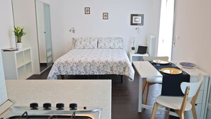 A compact bedroom with a bed, bedside table, and a small desk with a chair.