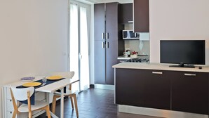 A modern kitchen with dark cabinets, a microwave, a stove, and a flat-screen TV.