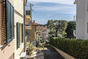 A narrow alleyway with a staircase leading to a building with a balcony.