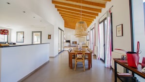 A spacious hallway with a wooden ceiling, a dining area with a table and chairs, and a kitchen area with a counter and appliances. - Villa Son Paparra in the center of Mallorca. (Montuiri)