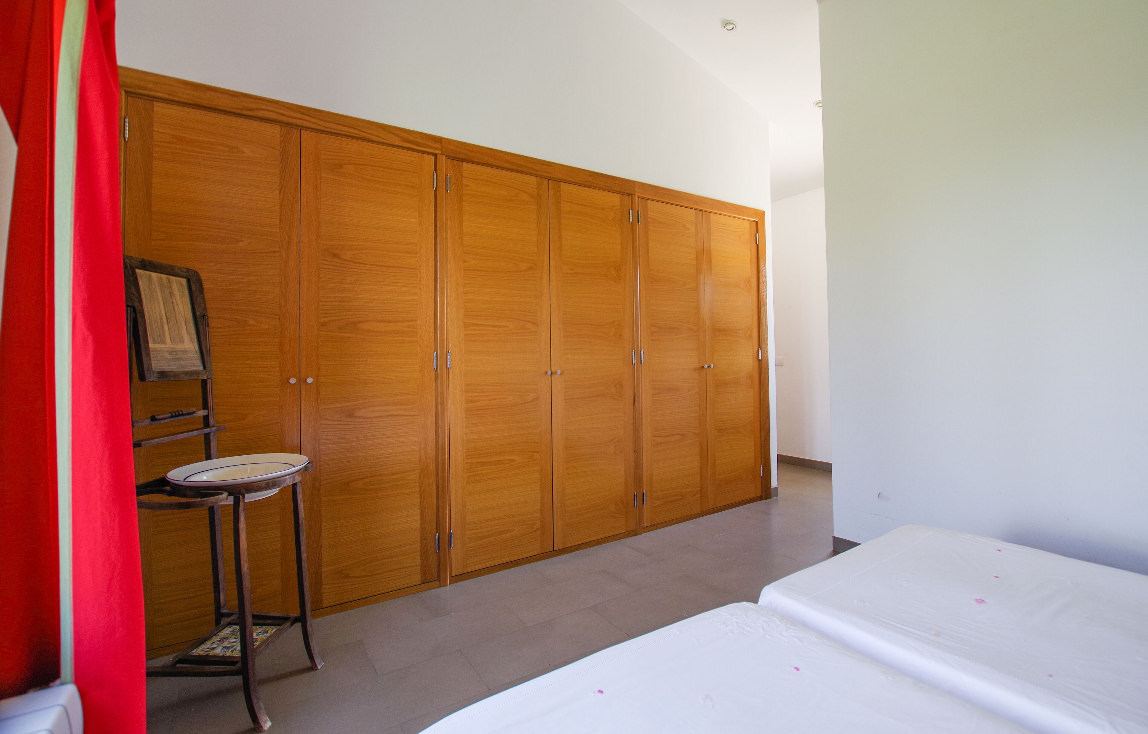 A bedroom with a large wooden wardrobe, a small round table, and a bed.
