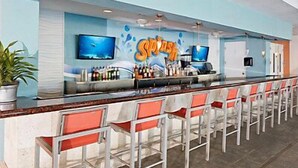 A bar area with a long counter, multiple bar stools, and a television screen. - Close to SeaWorld Spacious Two Bedroom w/ pools, hot tubs, bbq pits and family adventures (Orlando)