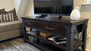 A modern living room with a dark wooden TV stand, a flat-screen TV, and a decorative pumpkin. - Your own modern treehouse overlooking Bidwell Park (Chico)
