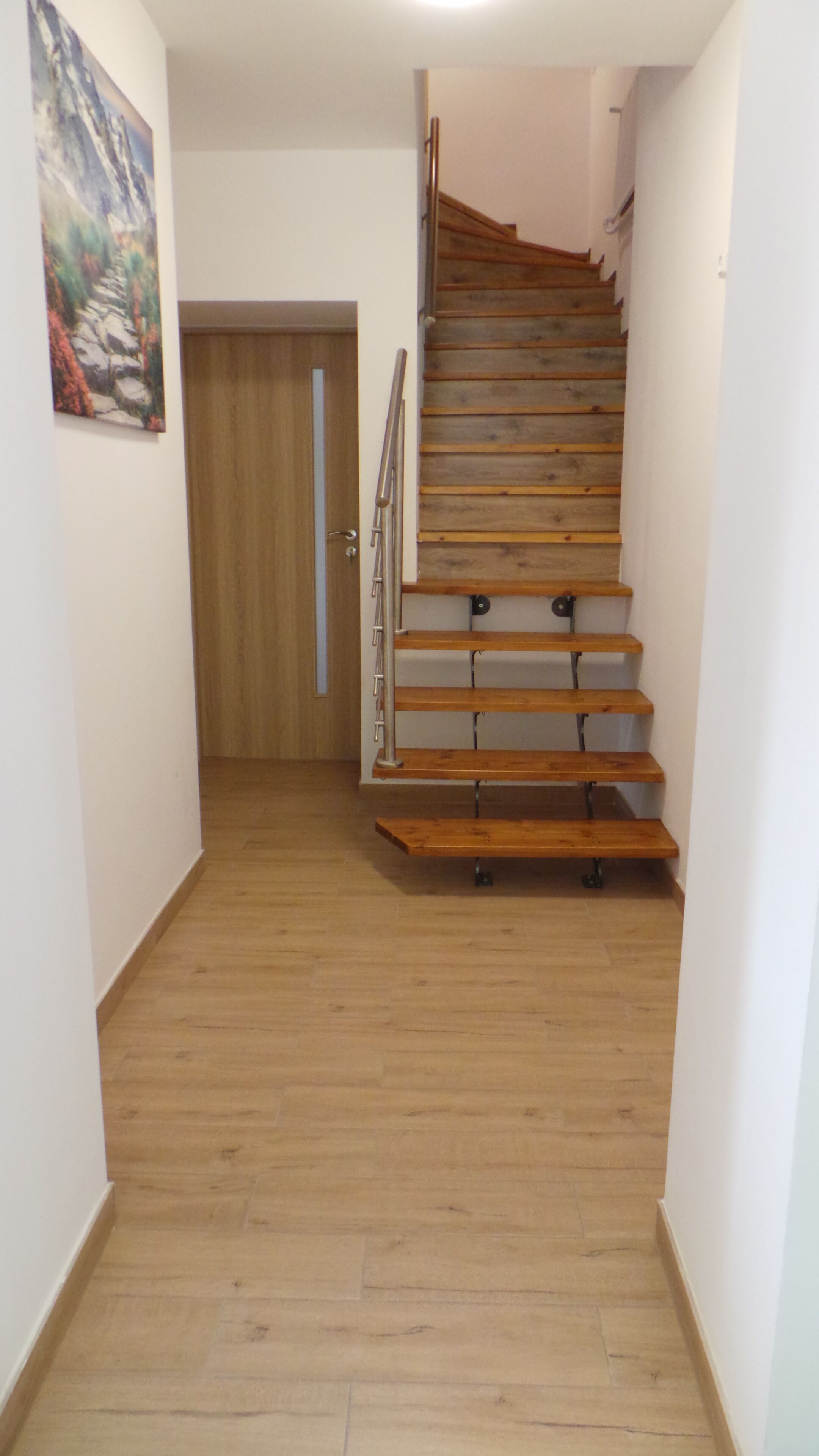 A wooden staircase with metal railings leading to a door.