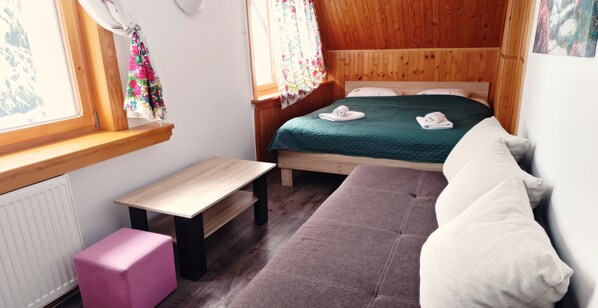Une pièce confortable avec un lit, une petite table, un banc et un canapé.