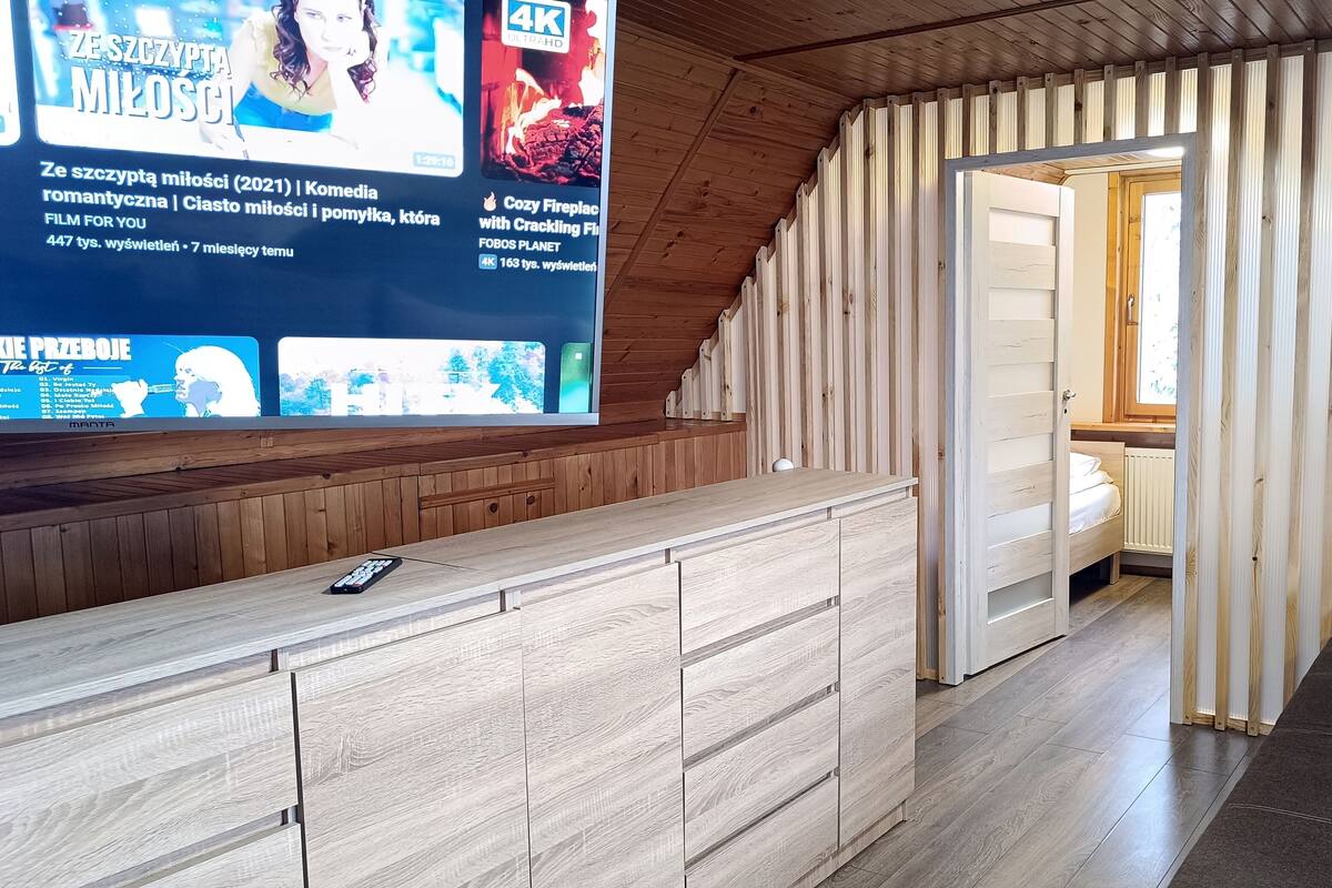 Un intérieur en bois avec un téléviseur diffusant un film et une cheminée chaleureuse.