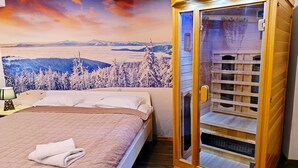 Een hotelkamer met een bed, een nachtkastje, een glazen kast en een muurschildering van een berglandschap.