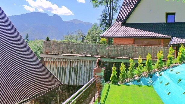 Iemand staat op een balkon met uitzicht op een bergachtig landschap.