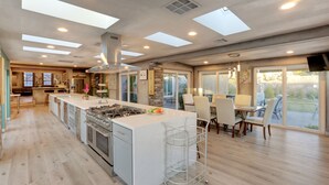 A spacious kitchen with a large island, modern appliances, and ample natural light from skylights.