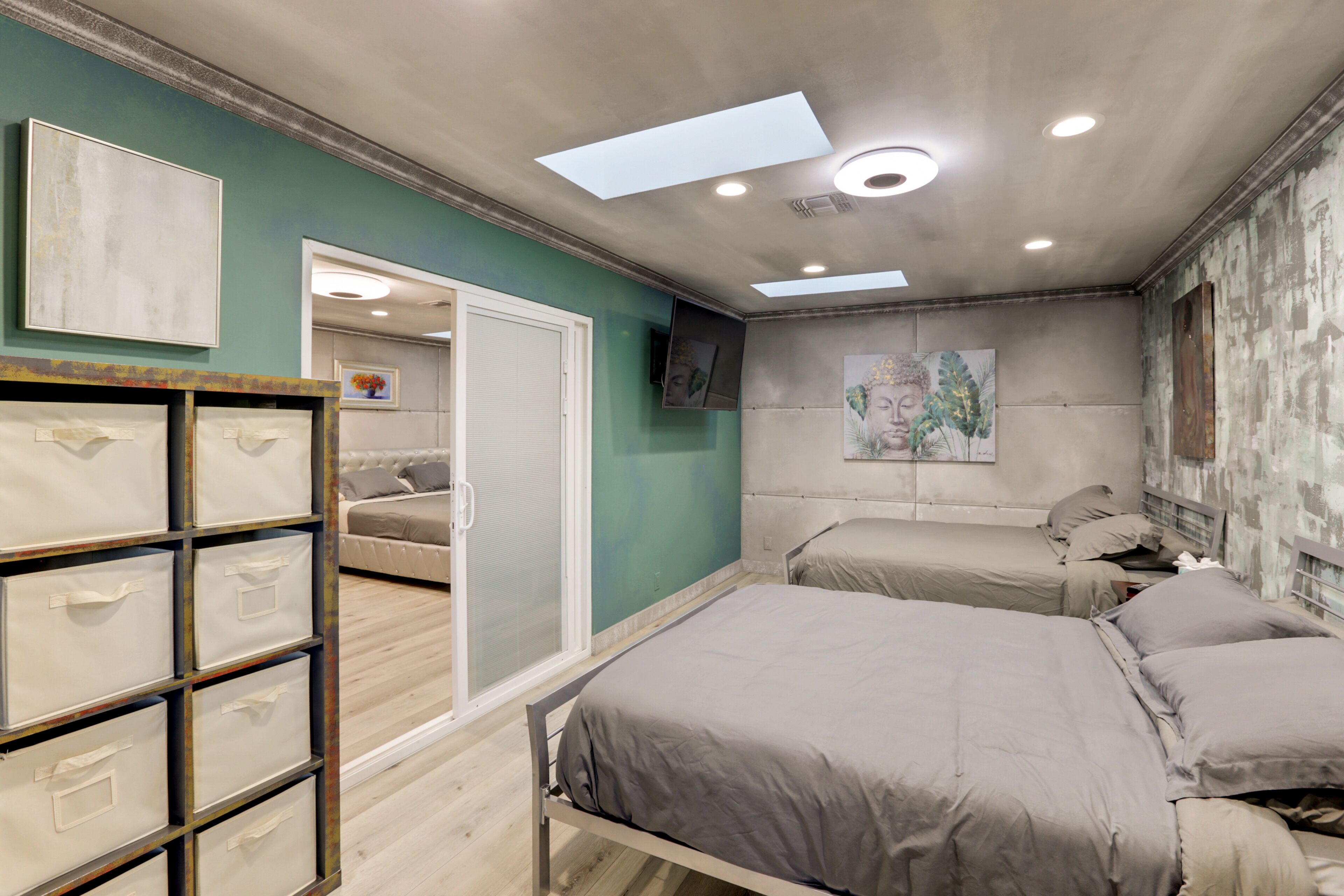 A bedroom with two beds, a wardrobe, and artwork on the walls.