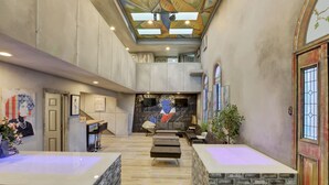 A spacious lobby with a high ceiling, a central seating area, and a staircase leading to an upper level.