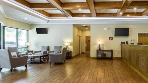 Eine geräumige Lobby mit Holzboden, einem Empfangsbereich und Sitzbereichen.