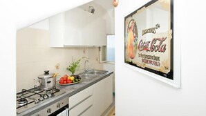 A kitchen with a gas stove, sink, and a framed Coca-Cola sign.