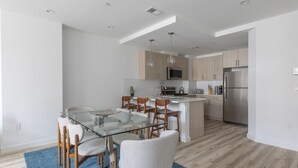Una cocina moderna con armarios de madera, un refrigerador de acero inoxidable y una mesa de comedor de vidrio con sillas.