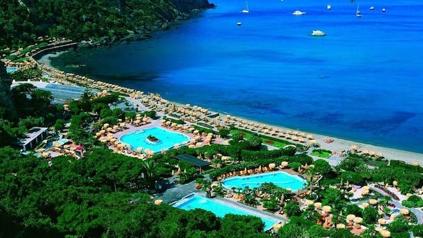 A resort with multiple swimming pools, a beach, and boats in the water.