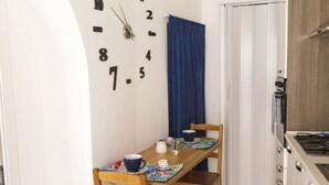 A small kitchen with a wooden table, chairs, a clock, and a stove.