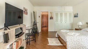A bedroom with a TV, a desk, a chair, a bed, and a door leading to another room. - FLH Vilamoura Cozy Studio (Vilamoura)