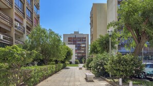 A pathway flanked by greenery and buildings, leading to a central structure with a modern design. - FLH Vilamoura Cozy Studio (Vilamoura)