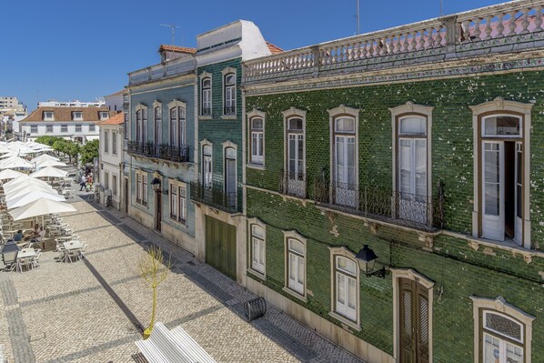 A street with buildings, outdoor seating, and a cobblestone path.