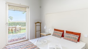 A hotel room with a bed, a bedside table, a nightstand, a chair, and a view of the outdoors. - FLH Cozy Tavira with Pool (Tavira)