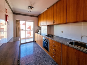 Una cucina con mobili in legno, piano cottura a gas, forno a microonde e lavello.