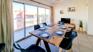 A dining area with a large table set for four, a television, and a potted plant. - FLH Praia da Rocha Spacious Flat (Portimão)