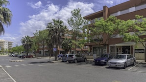 A parking lot with several cars parked in front of a building with multiple floors and a flat roof. - FLH Praia da Rocha Spacious Flat (Portimão)