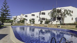 Piscina com muro de pedra e céu azul límpido.